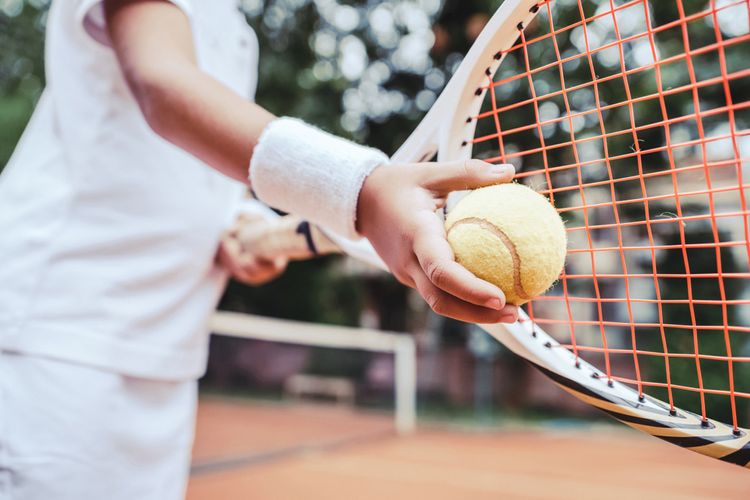 Dítě s tenisovou raketou se učí hrát tenis