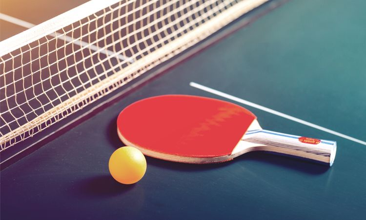 Pingpongový raketa položená na pingpongový stůl